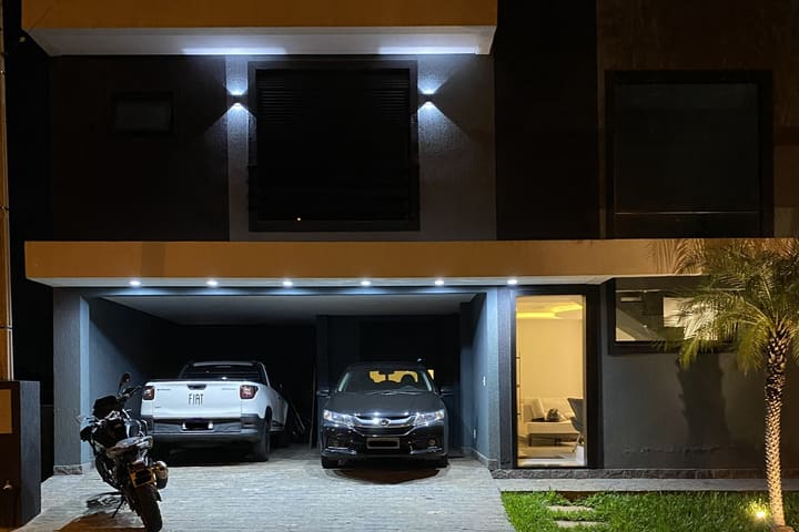 The house in Ponta Grossa at night, cars and a motorcycle in the garage.